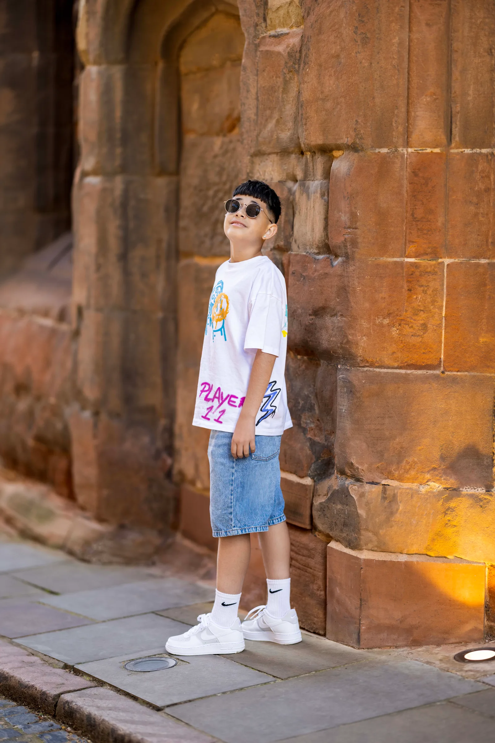 Teen boy in sunglasses posing against a sandstone castle wall