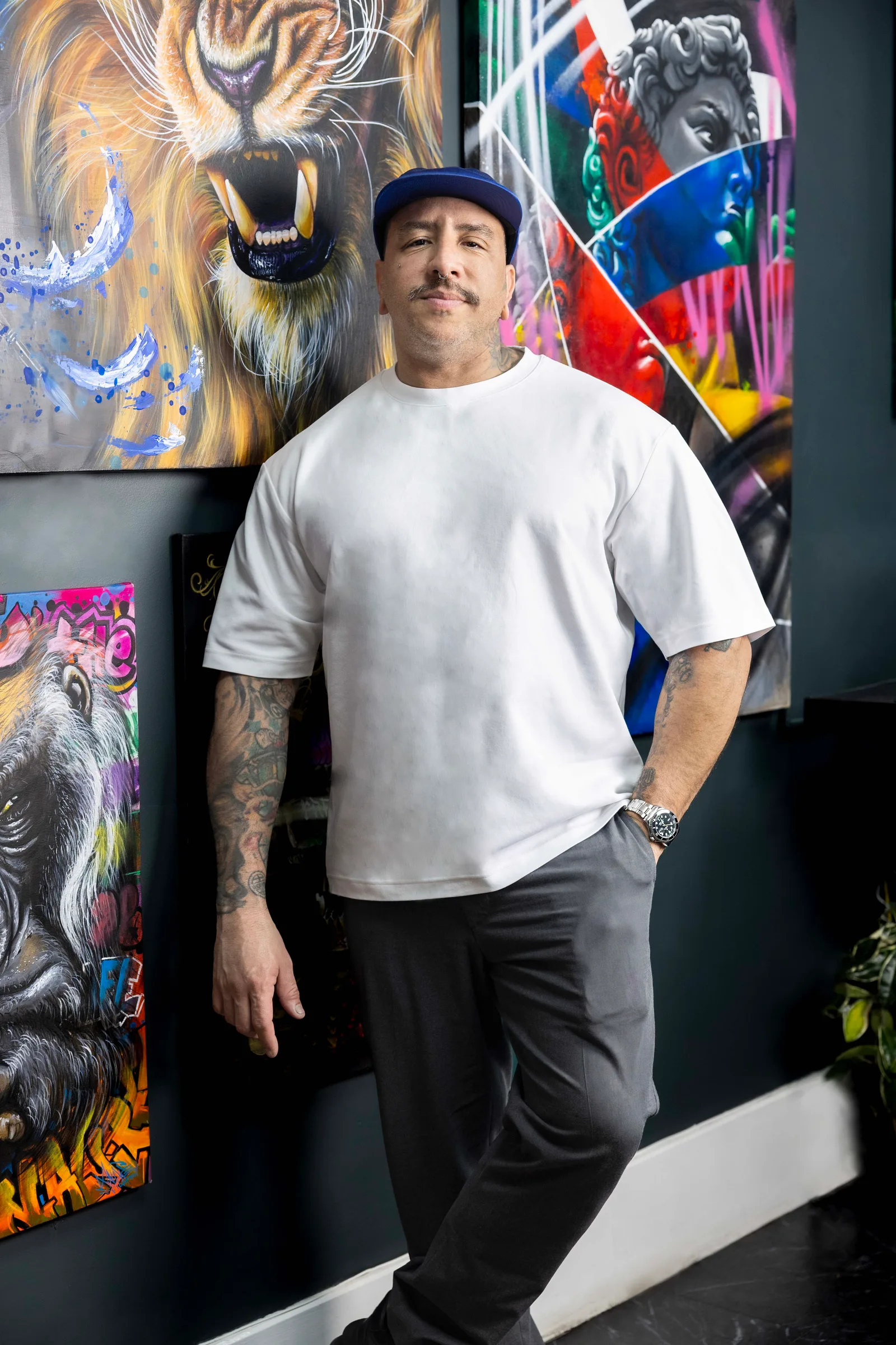 Relaxed yet striking pose set against a vibrant gallery wall of original paintings.