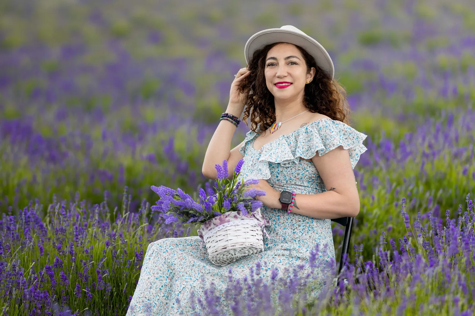 Woman in floral dress holding lavender bouquet seated in the field