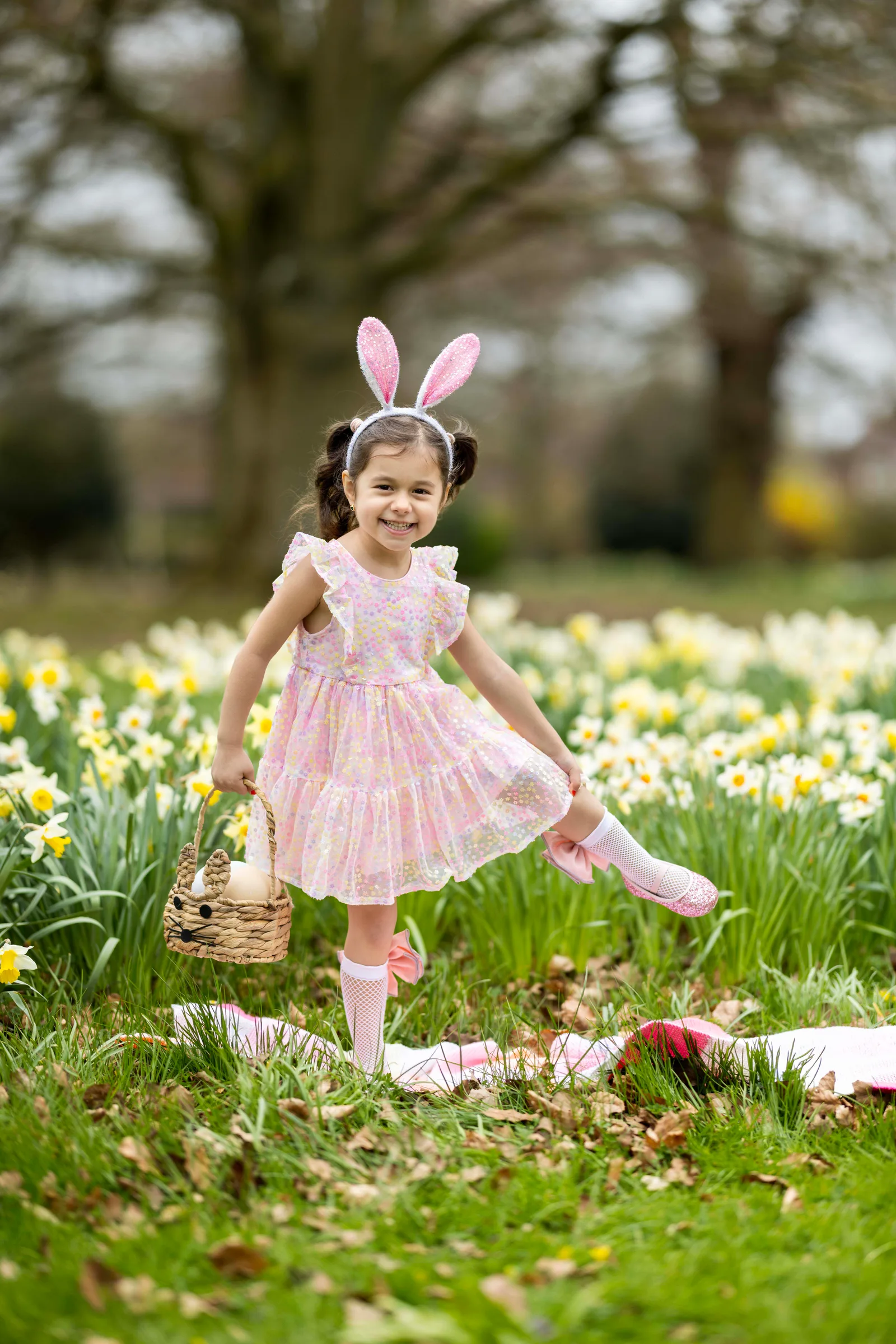 Girl in floral dress dancing among daffodils with a wicker basket
