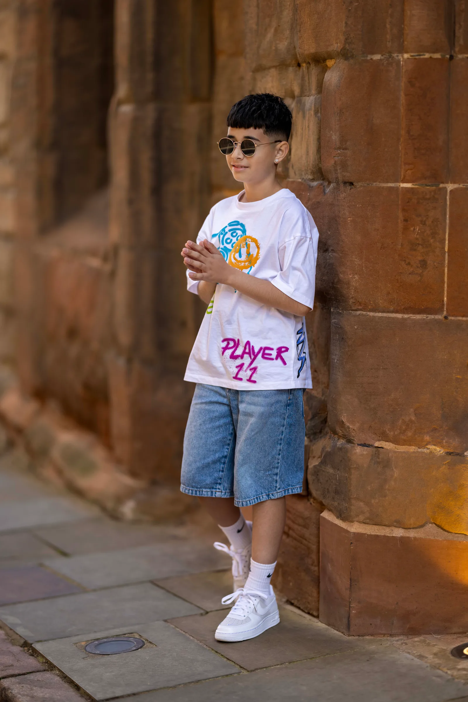 Teen boy in sunglasses leaning against a stone archway