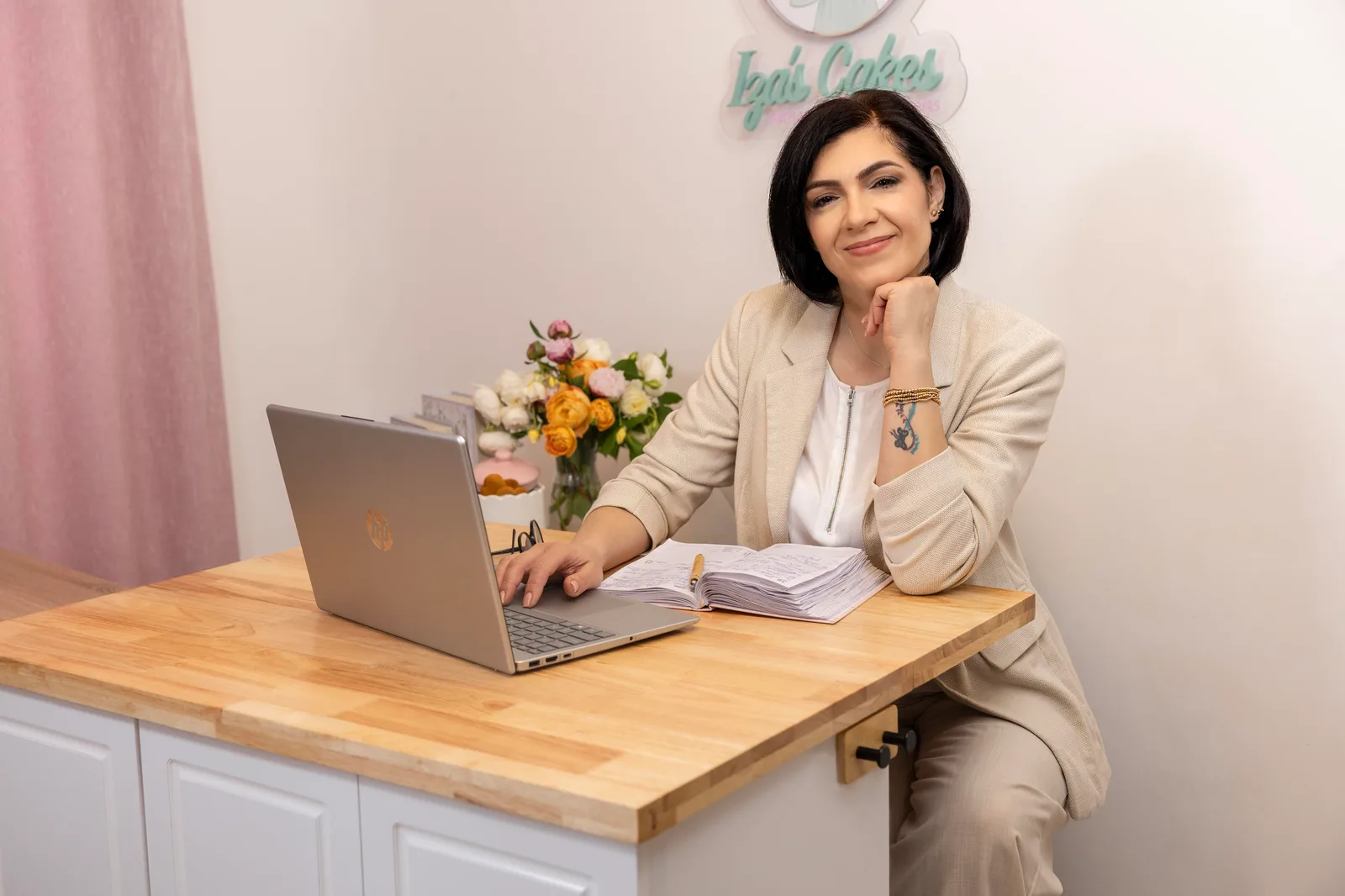 Woman working at a desk with a laptop and fresh flowers in a bright studio