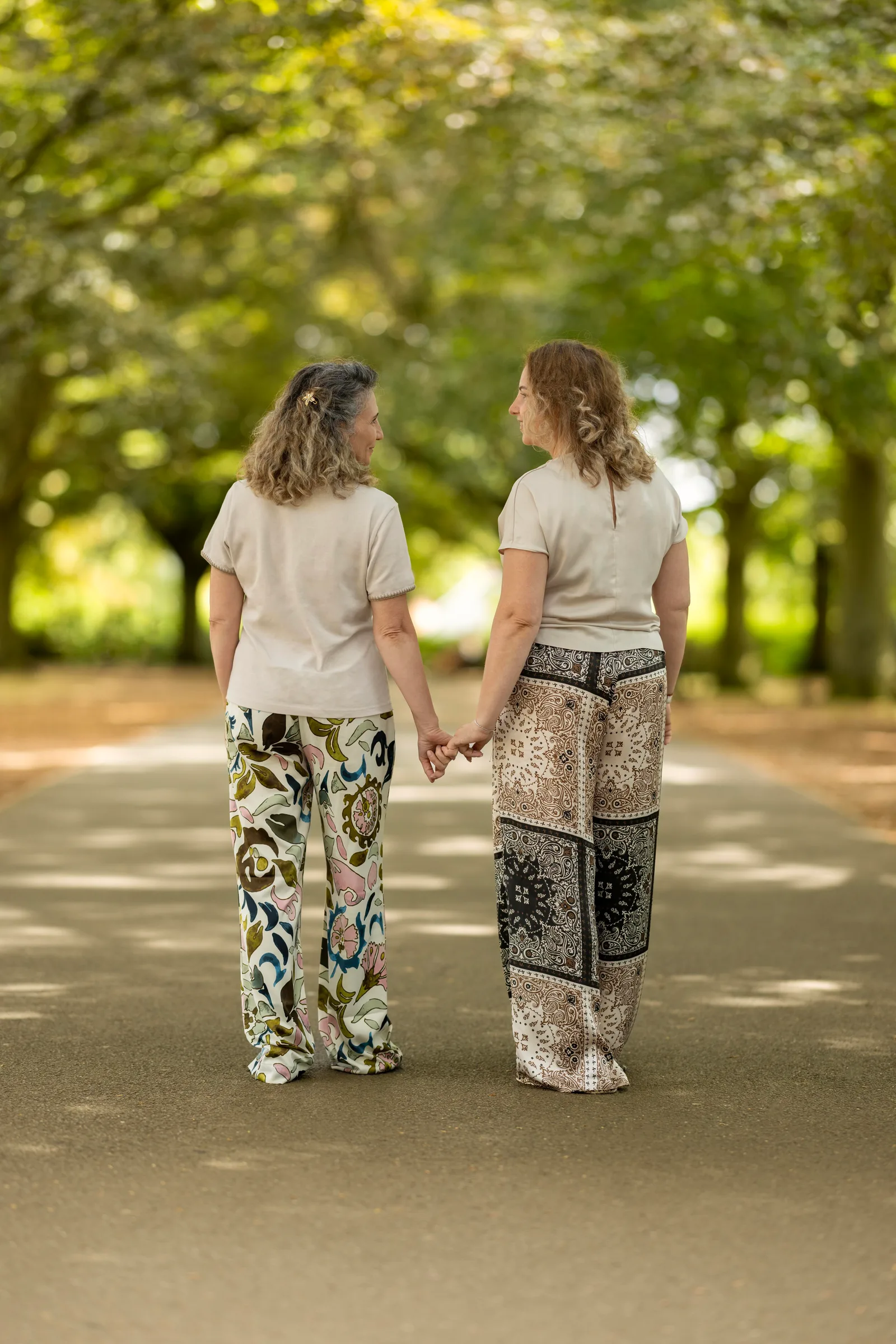 Two women walking together on a path, one turning to look at the other